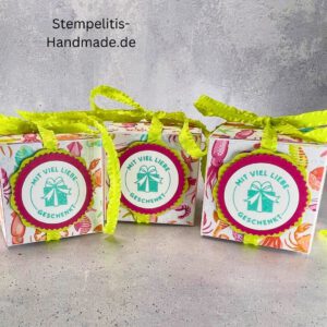 Handdekorierte Geschenkschachtel mit Schleife von oben, Geschenkschachtel mit liebevollem Aufkleber “Mit viel Liebe verschenkt”, Detailansicht Schleife auf Geschenkschachtel, Seitenansicht Geschenkschachtel mit buntem Designpapier, Offene Geschenkbox zum Befüllen, Geschenkschachtel auf hellem Hintergrund mit Dekorband, Handgemachte Geschenkverpackung mit grünem Band und Etikett